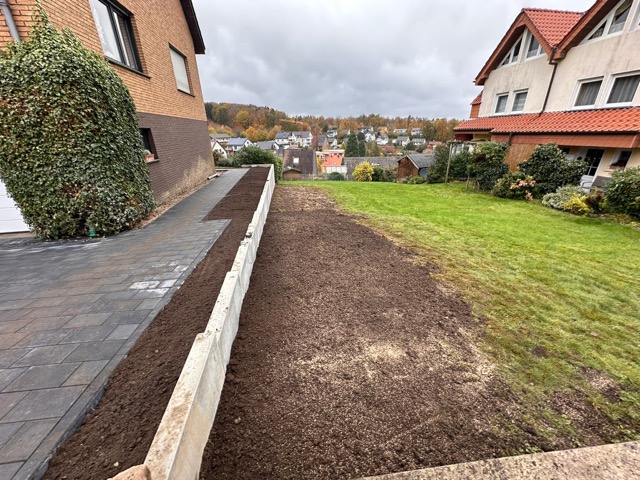 Zwei Wohnhäuser in ländlicher Gegend, mit gepflegtem Rasen und frisch bearbeiteter Erdfläche.