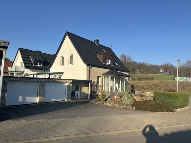 Ein zweistöckiges Einfamilienhaus mit Satteldach und Doppelgarage in ruhiger, sonniger Wohngegend.